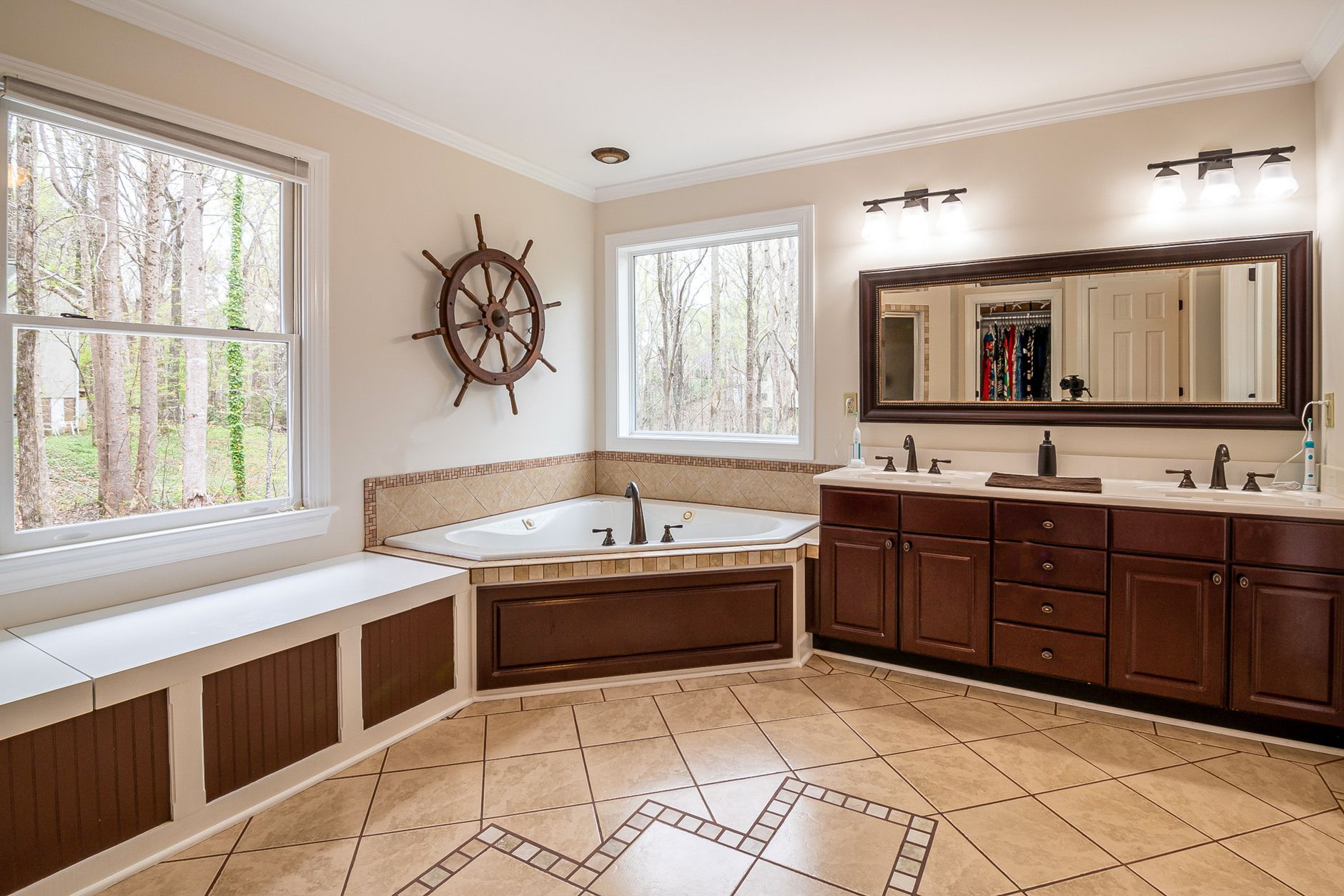 Spacious bathroom featuring a large corner bathtub, wooden cabinets, and natural light from large windows in Riverside, CA