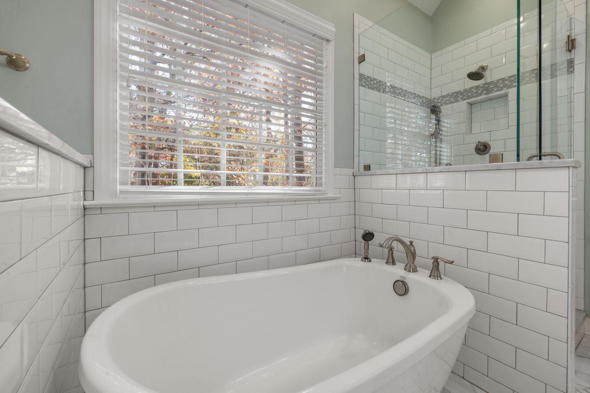 A spacious bathroom featuring a luxurious freestanding tub and glass shower surrounded by subway tiles in Riverside, CA